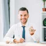 Agent immobilier montrant une maison de jouet